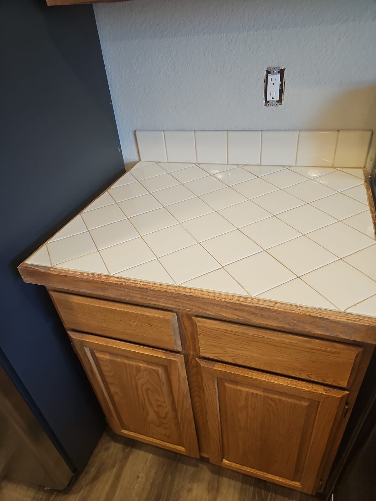 Close-up of tiled countertop with wooden cabinets