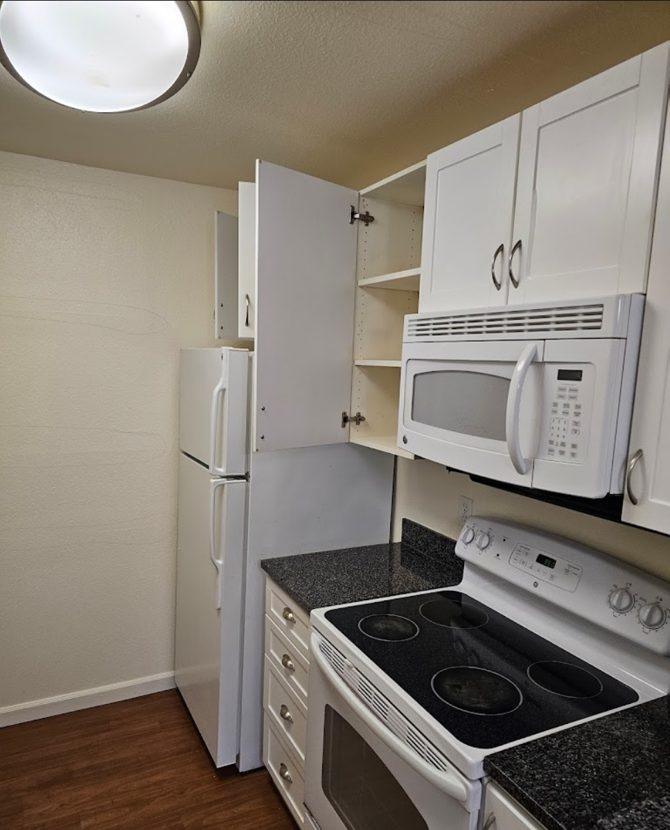 Compact kitchen with white cabinets and integrated appliances